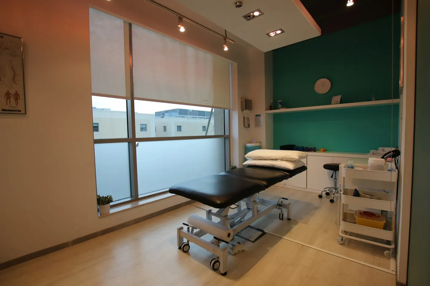 Sala de tratamento com marquesa, luz natural e parede verde